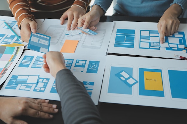 Close up ux developer and ui designer brainstorming about mobile app interface wireframe design on table with customer breif and color code at modern officeCreative digital development agency