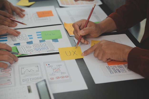 Close up ux developer and ui designer brainstorming about mobile app interface wireframe design on table with customer breif and color code at modern officeCreative digital development agency