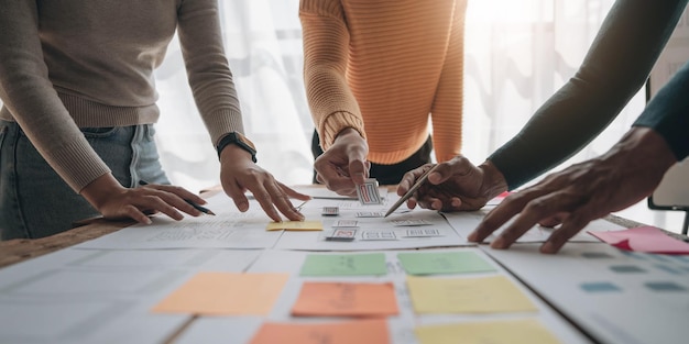 Close up ux developer and ui designer brainstorming about mobile app interface wireframe design on table with customer breif and color code at modern officeCreative digital development agency