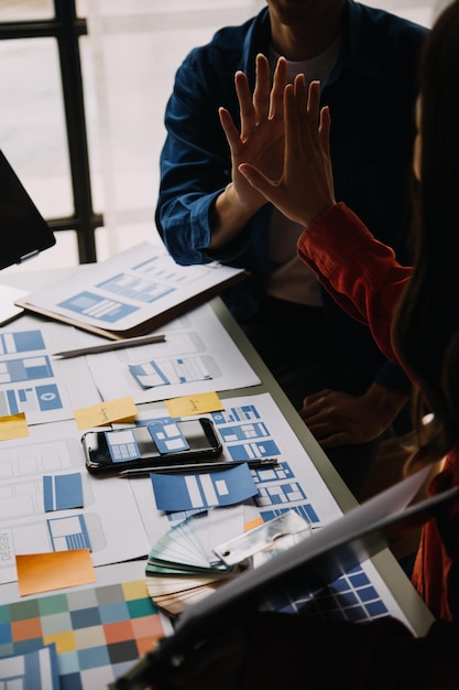 Close up ux developer and ui designer use augmented reality brainstorming about mobile app interface wireframe design on desk at modern officeCreative digital development agency