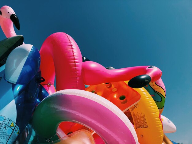 Photo close-up of various inflatables beach toys on beach against clear summer sky