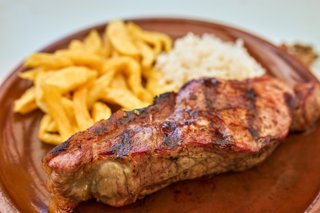 Close-up of veal cutlet with fried potatoes and rice.