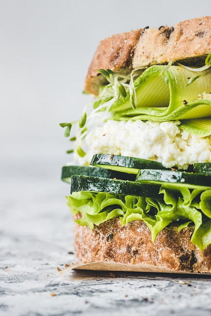 Photo close-up of vegetarian sandwich with green vegetables. lettuce, zucchini, alfalfa and cucumber. vegan food.