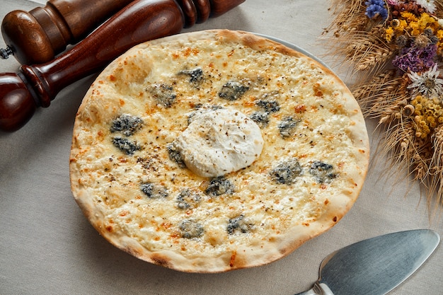 Close up view on Appetizing 4 cheese pizza on a linen gray tablecloth in a restaurant. Pizza in composition. Italian cuisine. Food flat lay