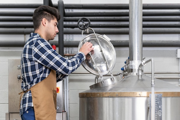 Close up view of an artisan brewer working at craft beer factory