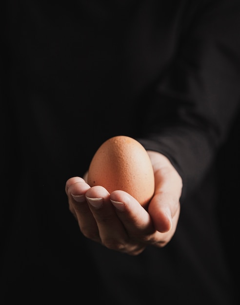 Close-up view baker hand holding egg