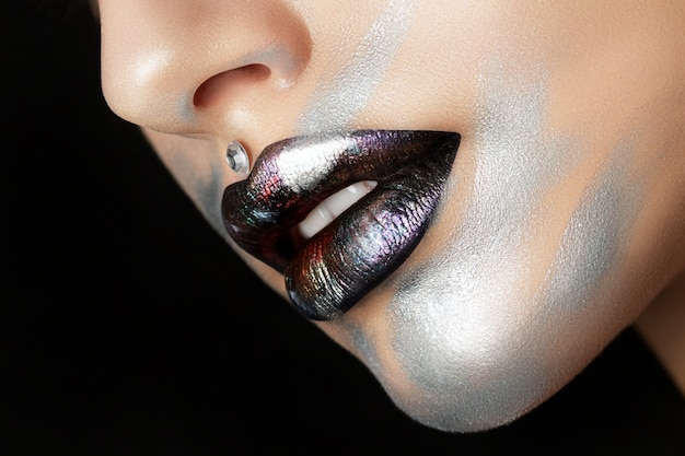 Close up view of beautiful woman lips with modern fashion makeup. Dark lips with colorful metallic tints.