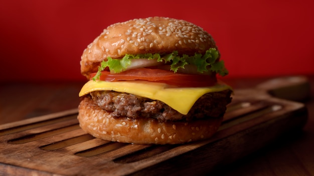 Close up view of beef burger on wooden tray on rustic table white red wall