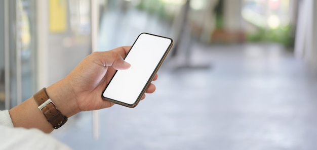 Close-up view of businessman holding blank screen smartphone with blurred office