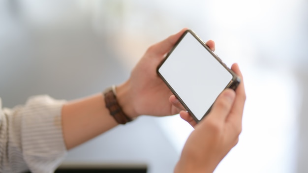 Close up view of businessman texting on smartphone while sitting on couch