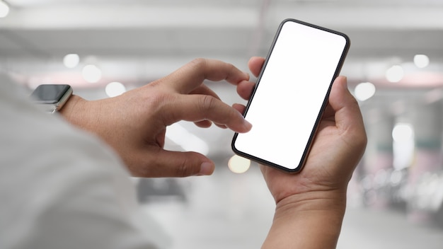 Photo close up view of businessman using blank screen smartphone in car parking