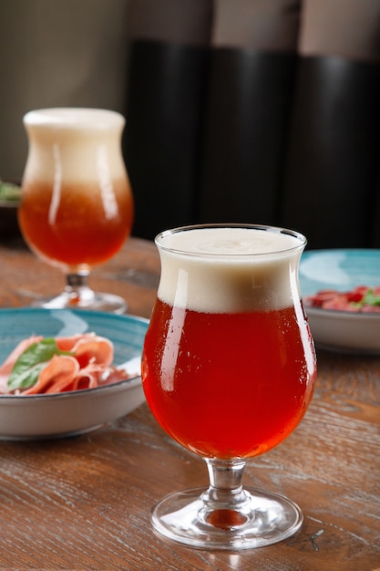 Close up view on cold amber beer in a glass with snack at bar on table