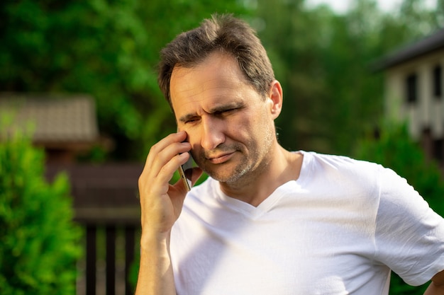 Close up view of confident handsome man talking on mobile phone outdoors. Businessman making phone call, calling on smartphone. Copy space, summer, communication, people, digital gadgets concept