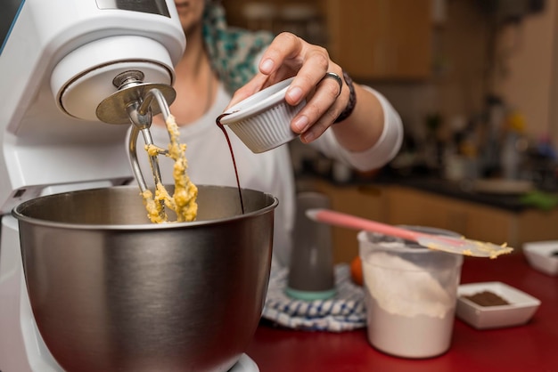 Close-up view of a cook's hand putting vanilla extract in a mixer bowl for the preparation of the homemade Argentine alfajores recipe.. Concept of regional, traditional food.