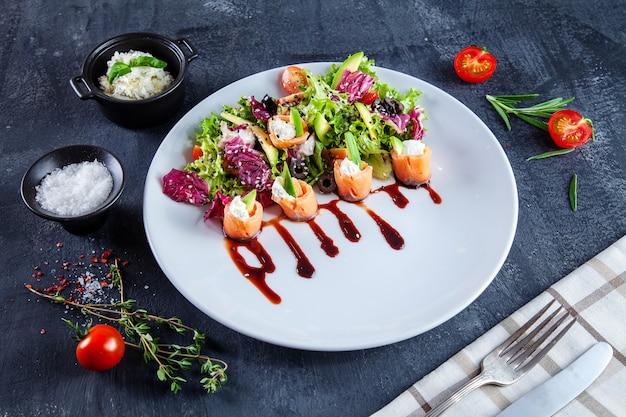 Close up view on delicious salad with salmon, cream cheese, avocado and brown soy sauce on dark background. Tasty, halthy salad for lunch on dark background. Seafood. Flat lay food