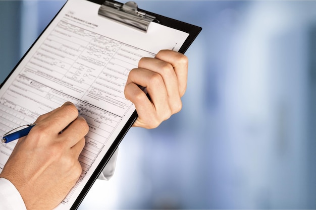 Close-up view of female doctor hands filling patient registration form