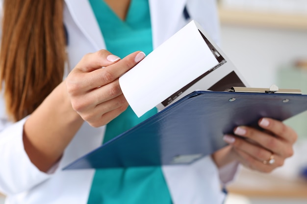 Close-up view of female doctors hands holding patient's medical record. Healthcare and medical concept