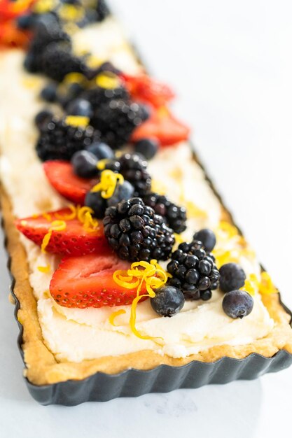 Close up view. Freshly baked mascarpone tart with fresh berries and garnished with lemon zest.