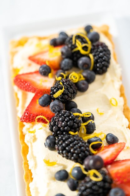 Close up view. Freshly baked mascarpone tart with fresh berries and garnished with lemon zest.