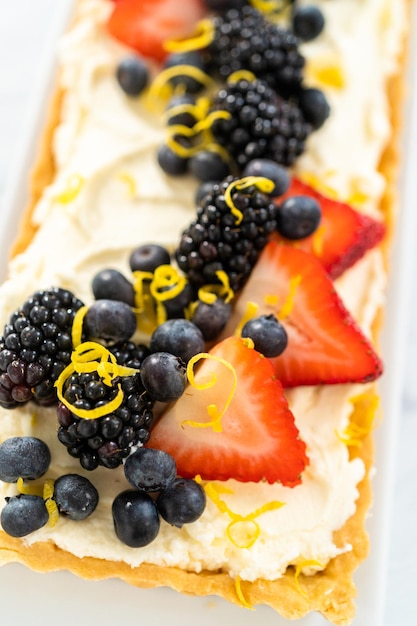 Close up view Freshly baked mascarpone tart with fresh berries and garnished with lemon zest