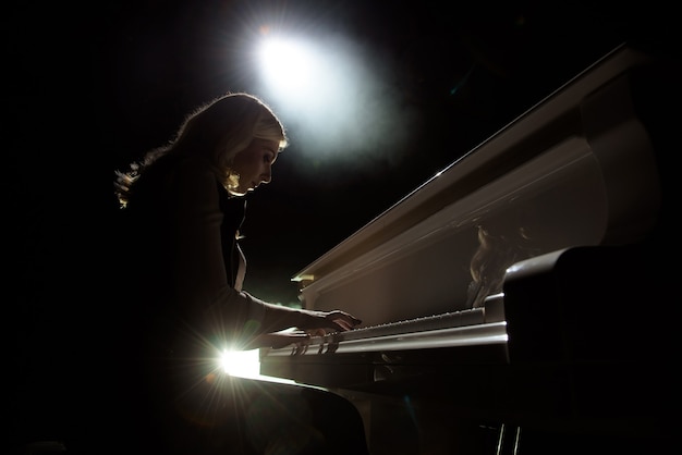 Close up view of a girl plays piano in the concert hall at the scene