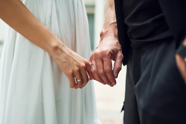 Close up view Holding by the hands Beautiful bride with his fiance is celebrating wedding outdoors