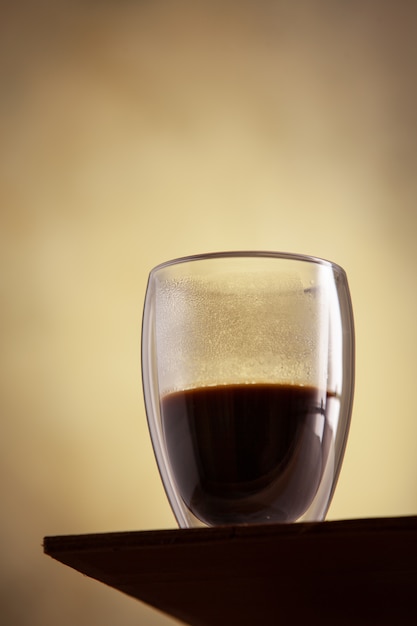 Close up view on hot glass of coffe stands in front of a concrete wall