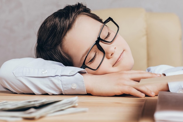 Close up view of little tired boy sleeping on table at workplace