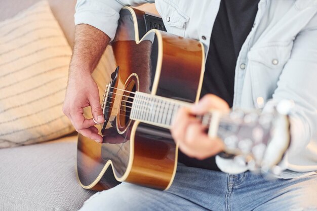 Close up view Man in casual clothes and with acoustic guitar is indoors