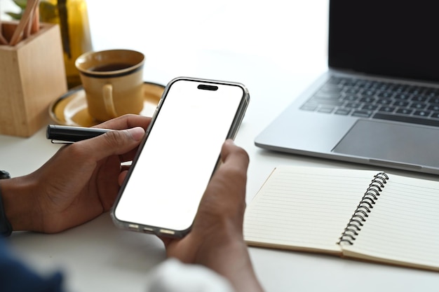 Close up view of man sitting on bright office and using smart phoneEmpty screen for your advertise design