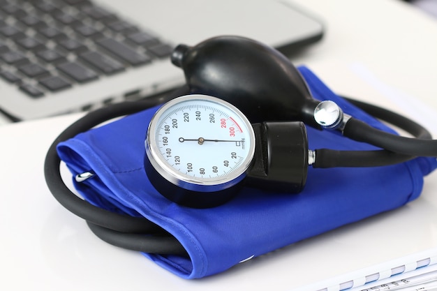 Close up view of manometer laying on working table near laptop. Hospital workspace. Healthcare, medical service, treatment, hypotonia or hypertension concept.