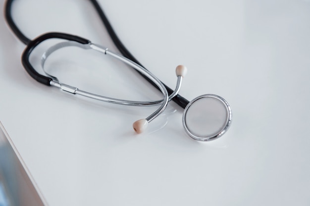 Close up view of medical stethoscope that lying down on white table