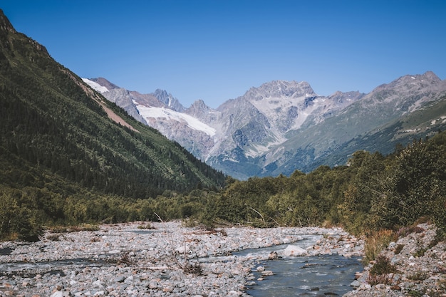 Close up view mountains and river scenes in national park Dombai, Caucasus, Russia, Europe. Summer landscape, sunshine weather, dramatic blue sky and sunny day