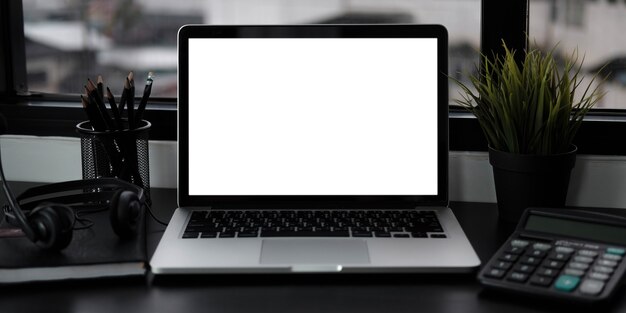 Close-up view of open blank screen laptop computer with office supplies in modern office