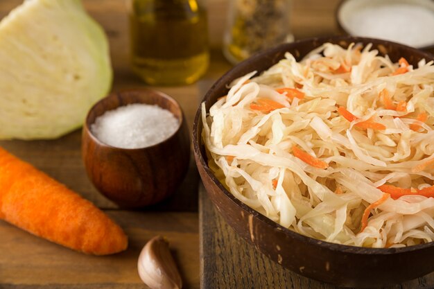 Close up view of part of bowl of sour sauerkraut carrots salt and olive oil