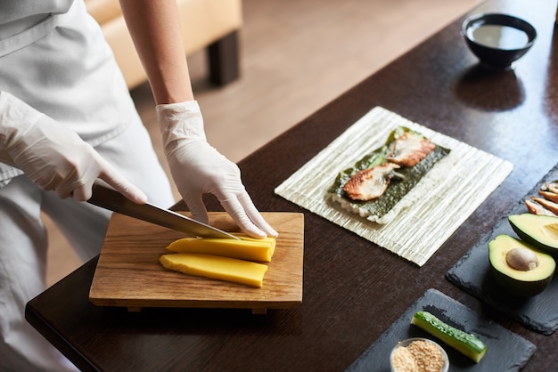 Close-up view of process of preparing rolling sushi