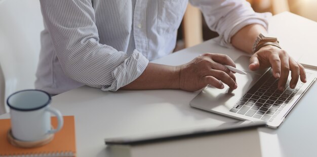 Close-up view of professional businessman typing on laptop computer while working on his project 