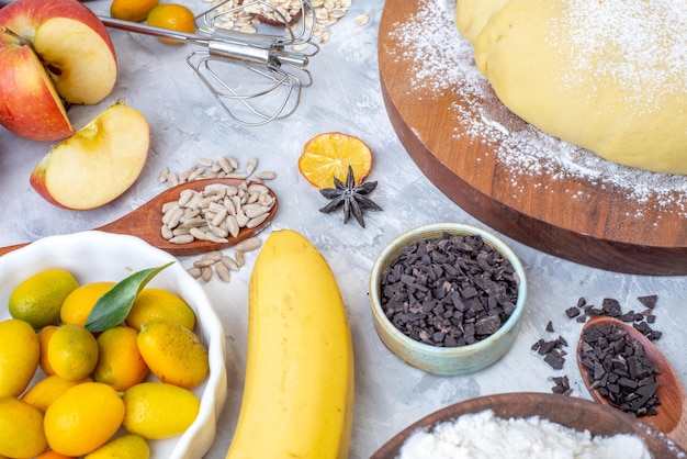 Close up view of raw pastry flour on round wooden board oatmeal fresh fruits jam on gray background