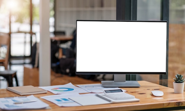 Close up view of simple workspace with open blank screen laptop, frame and notebook on white table with blurred office room background