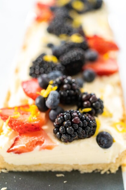 Close up view Sliced mascarpone tart with fresh berries garnished with lemon zest