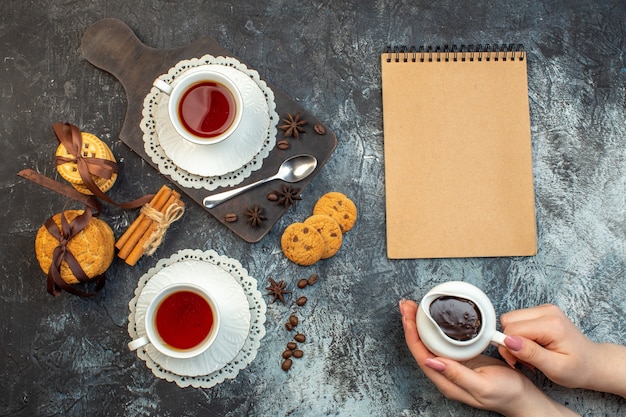 Close up view of stacked cookies cinnamon limes on wooden cutting board and tea notebook on ice background