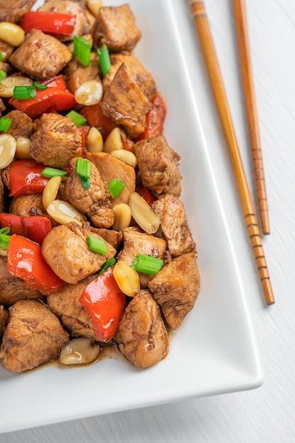 Photo close up view of stirfried chinese kung pao chicken with peanut and pepper with chopsticks