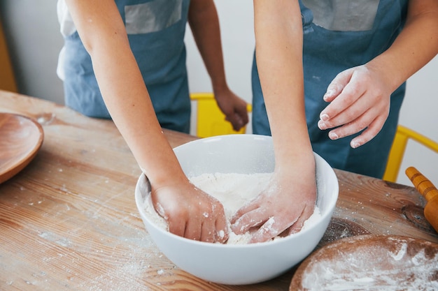 Close up view of two little girls in blue chef uniform that preparing food on the kitchen