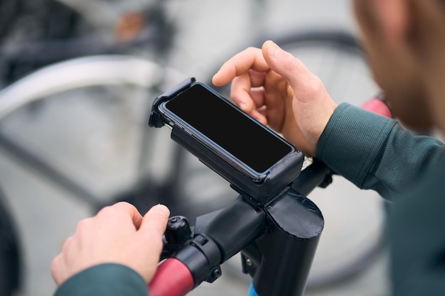 Close up view of the unknown man hands using mobile phone while unlocked scooter