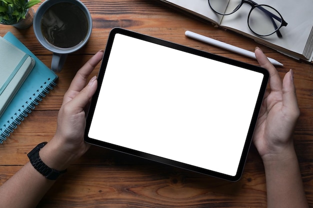 Close up view woman holding digital tablet with white screen on wooden table