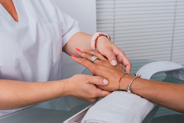 Close up view of a woman receiving manicure from beautician in the beauty spa.