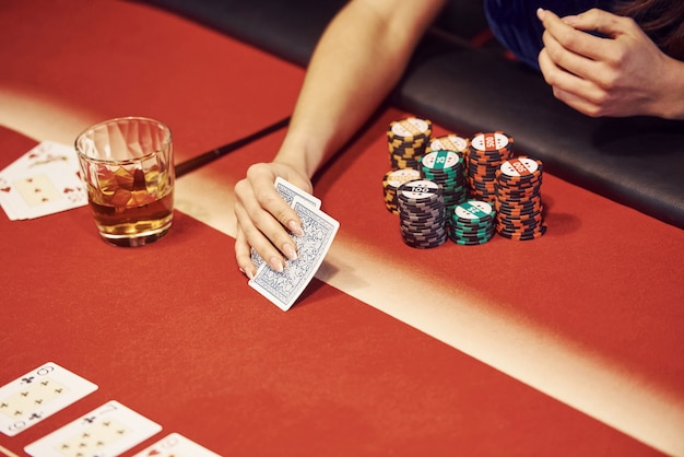 Close up view of woman's hands. Girl plays poker game by table in casino