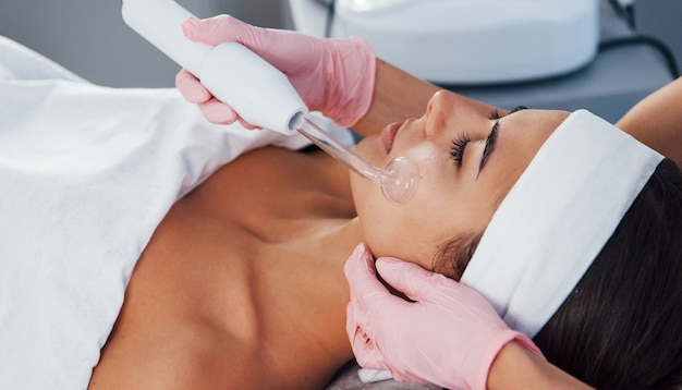 Close up view of woman that lying down in spa salon and have face cleaning procedure by using modern device.