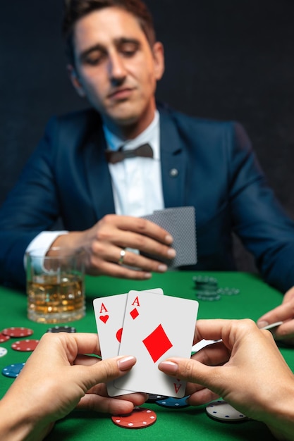 Close up view of women hand's with playing cards and chips at green casino table with poker player