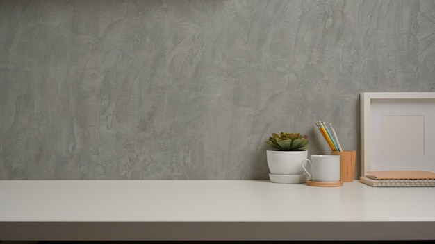 Close up view of workspace with decorations and copy space on white table with loft wall background